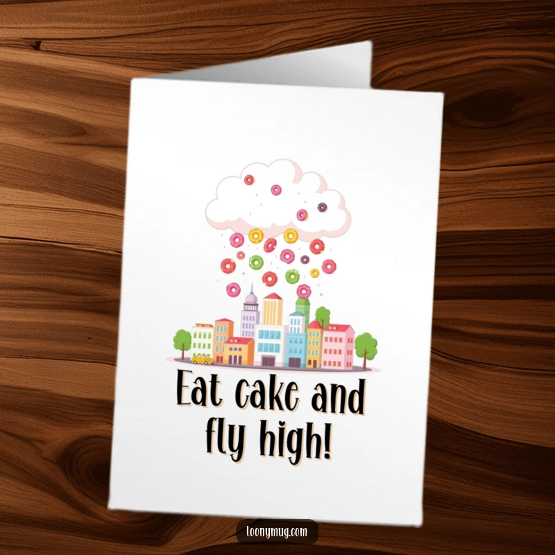 Funny free printable birthday card featuring a cheerful cloud raining colorful donuts on a miniature city, spreading joy.