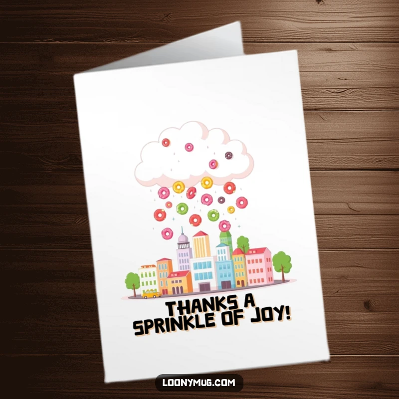 Funny free printable thank you card: a whimsical cloud rains vibrant donuts over a tiny cityscape, a sweet gesture.