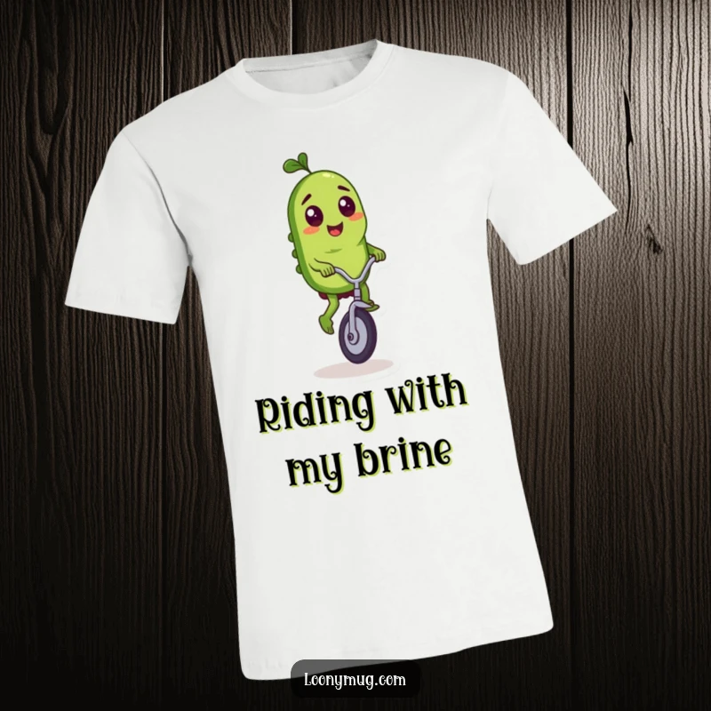 Funny t-shirt showcasing a mischievous pickle character performing a daring feat on a tiny unicycle.